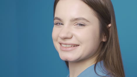 Ukrainian-woman-looks-at-camera-and-laughs.-Happy-and-cute.-Blue-background.